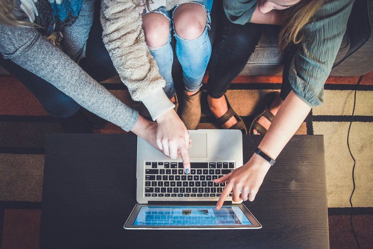 A group of people pointing at a laptop screen