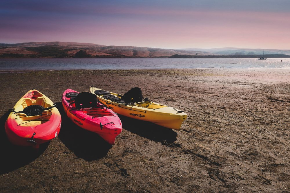three kayaks on the beach next to the ocean