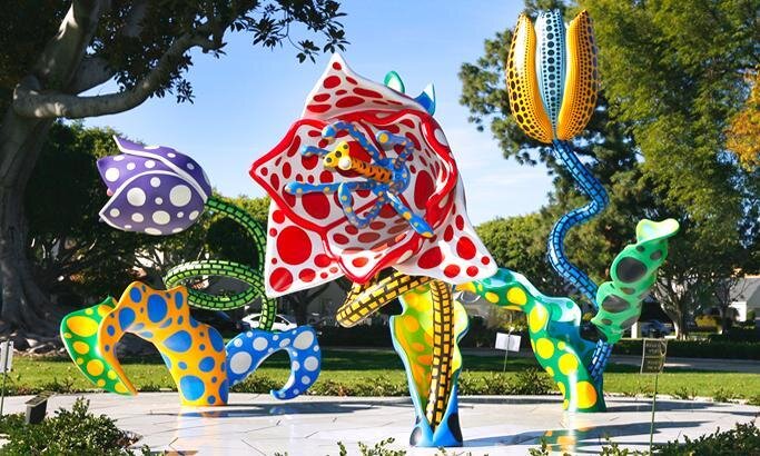 Three colorful outdoor art sculptures surrounded by greenery 