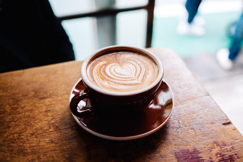 a latte with latte art resting on a table