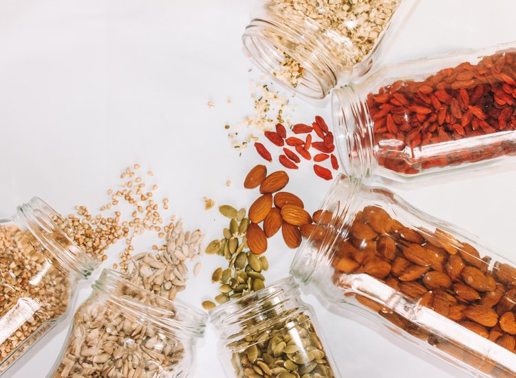 five glass jars on their sides with various dried goods spilling out of them