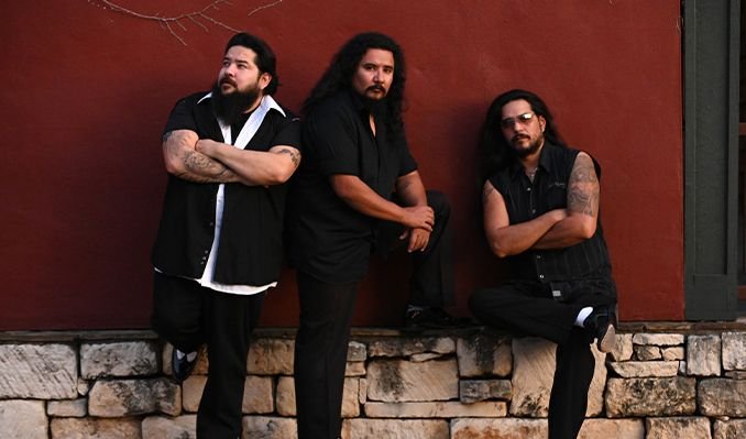The three members of the Los Lonely Boys posing with their arms crossed