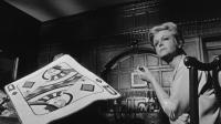 Image from the film 'The Manchurian Candidate' featuring someone sitting next to a large playing card
