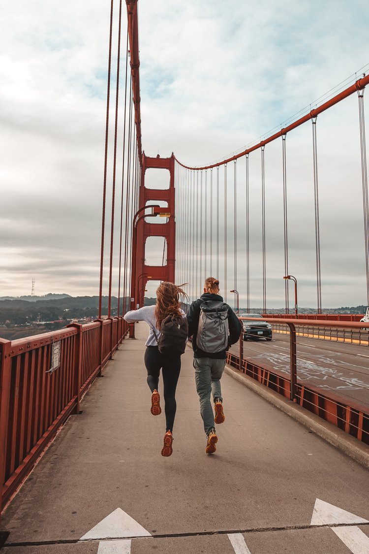 A pair of people skipping while crossing the Golden Gate Bridge