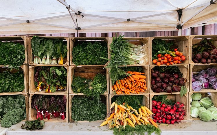 Various produce arranged in boxes at a farmer's market display