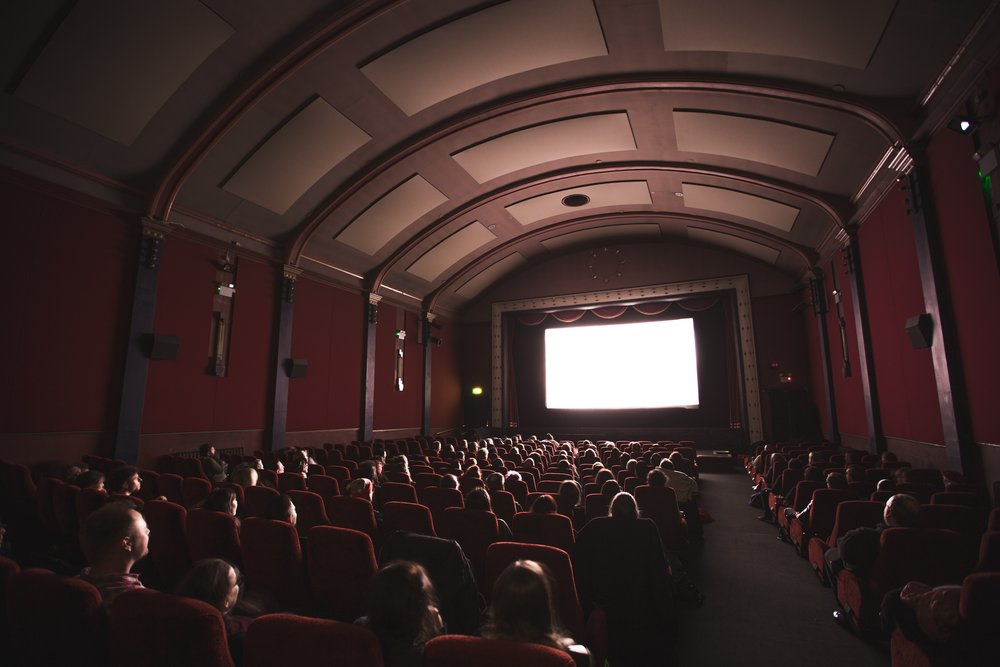 the back view of people sitting in a dark movie theater