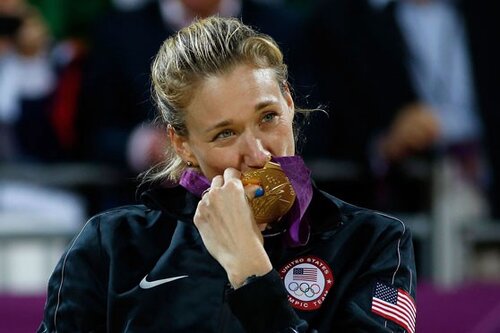 An Olympic Medalist kissing her Olympic gold medal with an emotional expression on her face