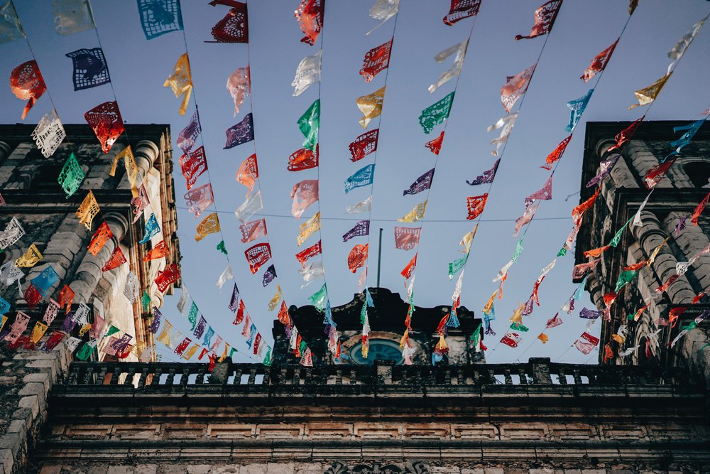 Mexican papel picado hanging on strings attached to a building