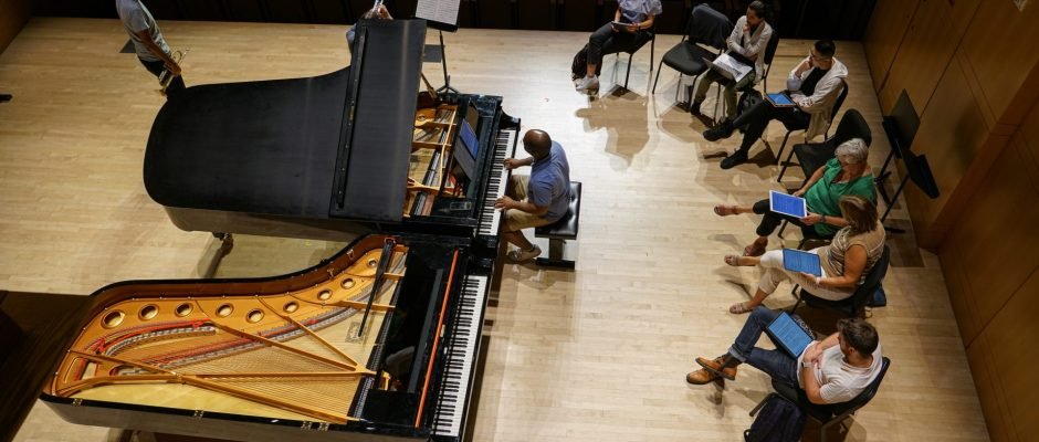 Someone performing the piano in front of a seated crowd 