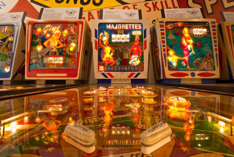 A row of colorful and lit-up pinball machines
