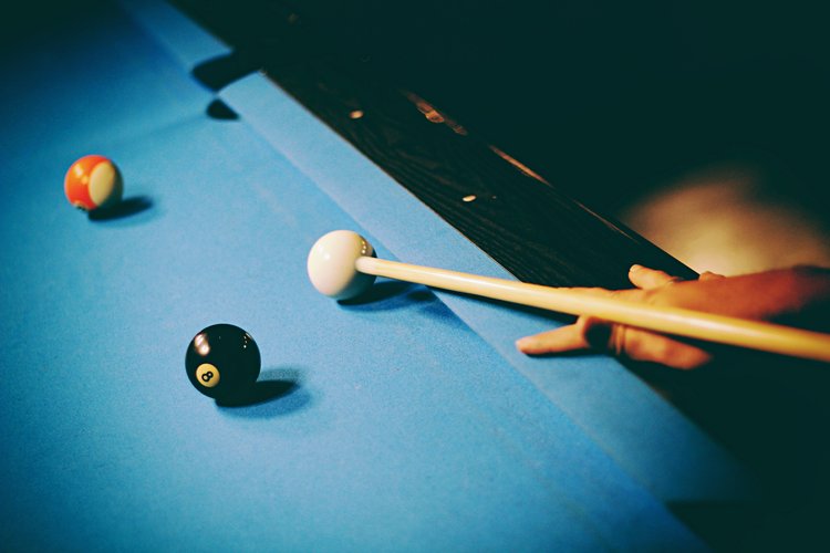 Someone playing pool on a blue pool table