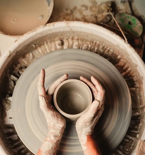 a person making pottery at a pottery wheel