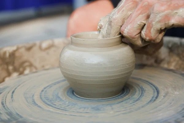 person making a pot on a pottery wheel