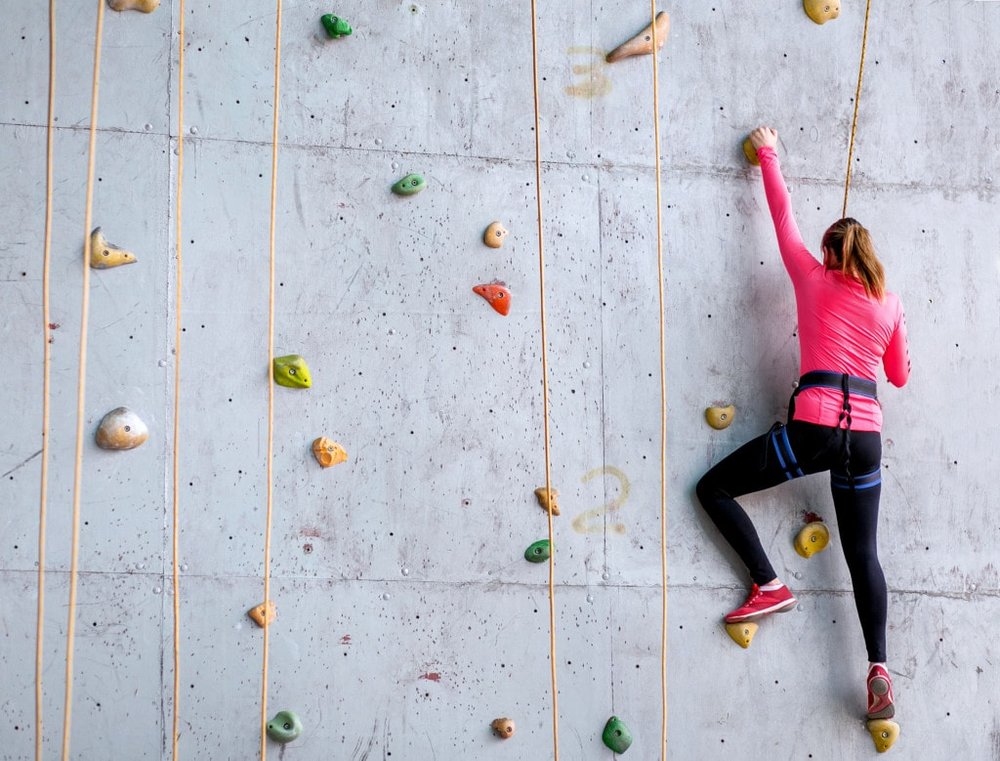 Someone wearing athletic clothing climbing an indoor rock wall 