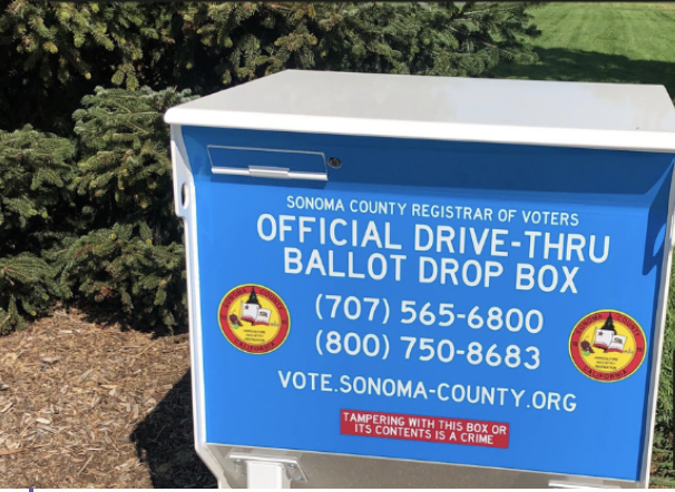 A blue and white ballot drop box with information in white text on the front 