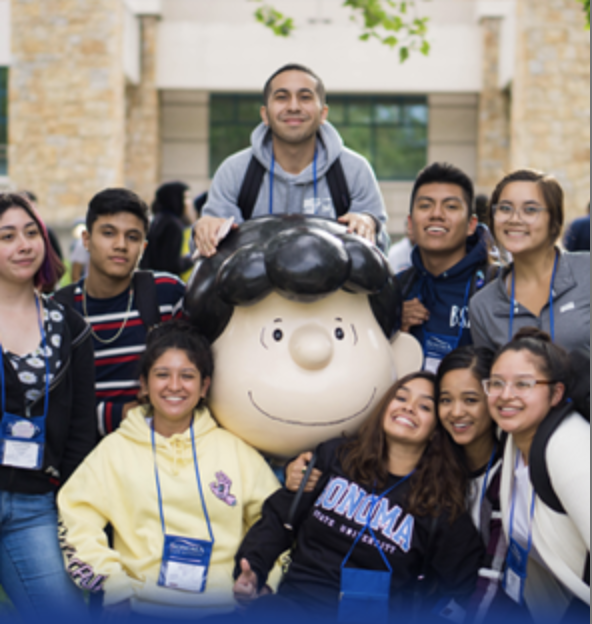 A group of students wearing name tags smiling and posing around the Lucy statue 