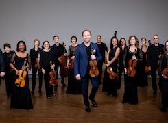 The members of the New Century Chamber Orchestra smiling while holding their instruments 