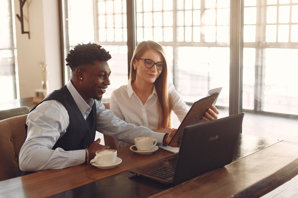 Two people smiling while looking at a laptop screen together