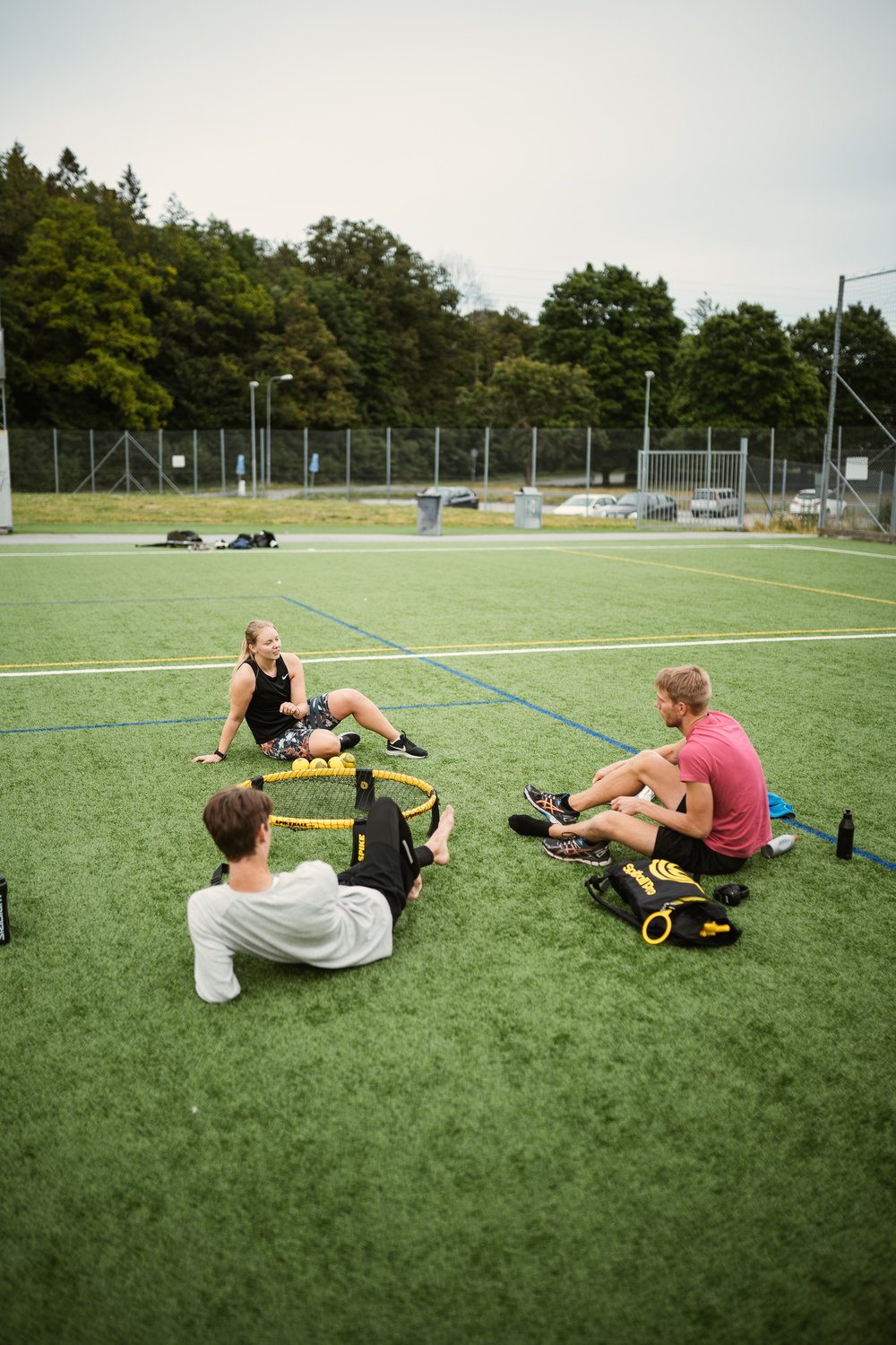people sitting on an field next to spikeball equipment