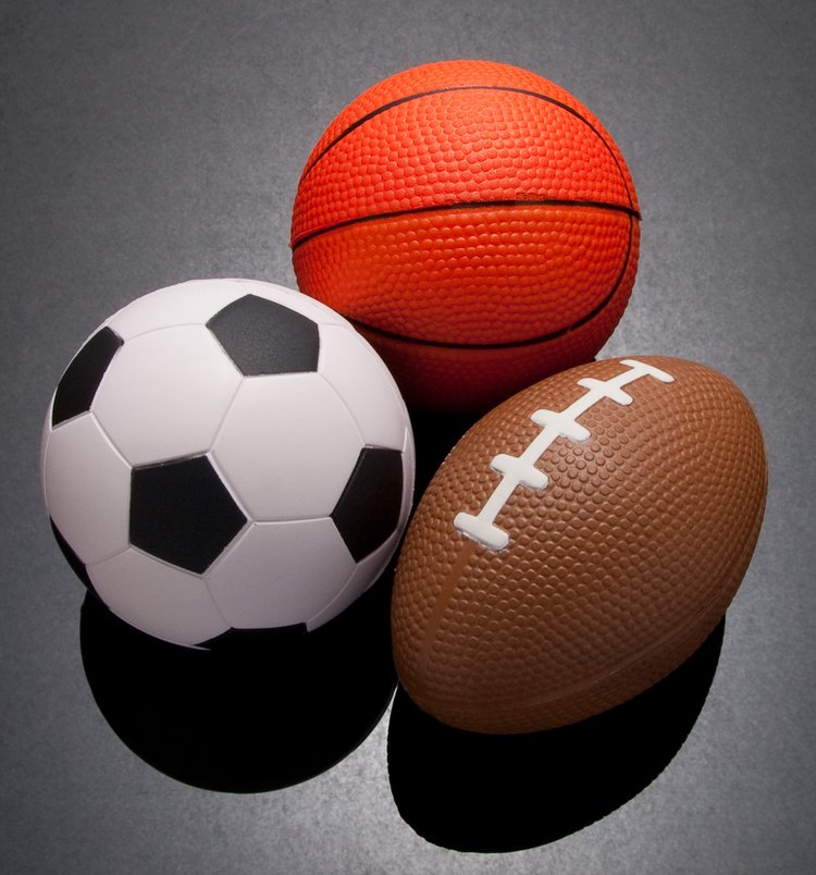 A soccer ball, a basketball, and a football