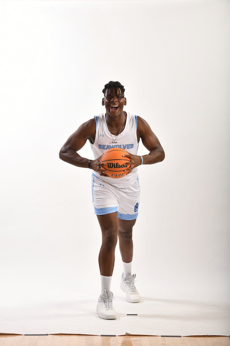 SSU Men's Basketball player Dillon Iyawe holding a basketball and smiling big for the camera