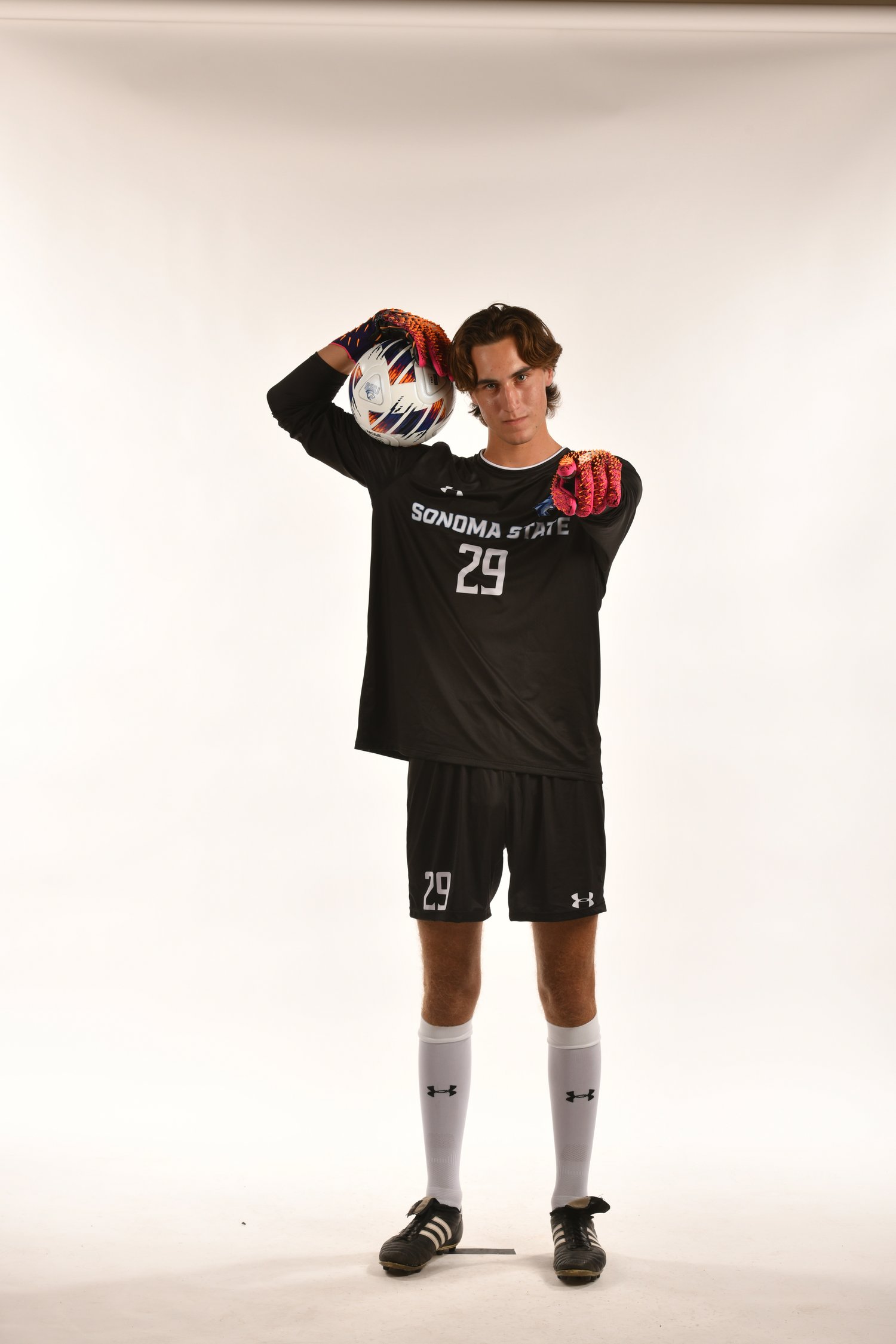 Sonoma State Men's Soccer team Goalkeeper Sammy Miller holding a soccer ball and pointing at the viewer