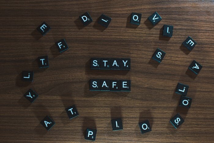 Black scrabble pieces arranged to spell "Stay Safe" with miscellaneous pieces surrounding