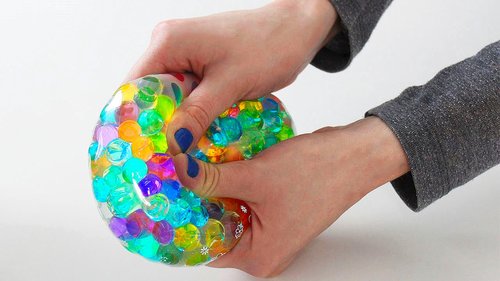 Two hands squeezing a colorful Orbeez stress ball 