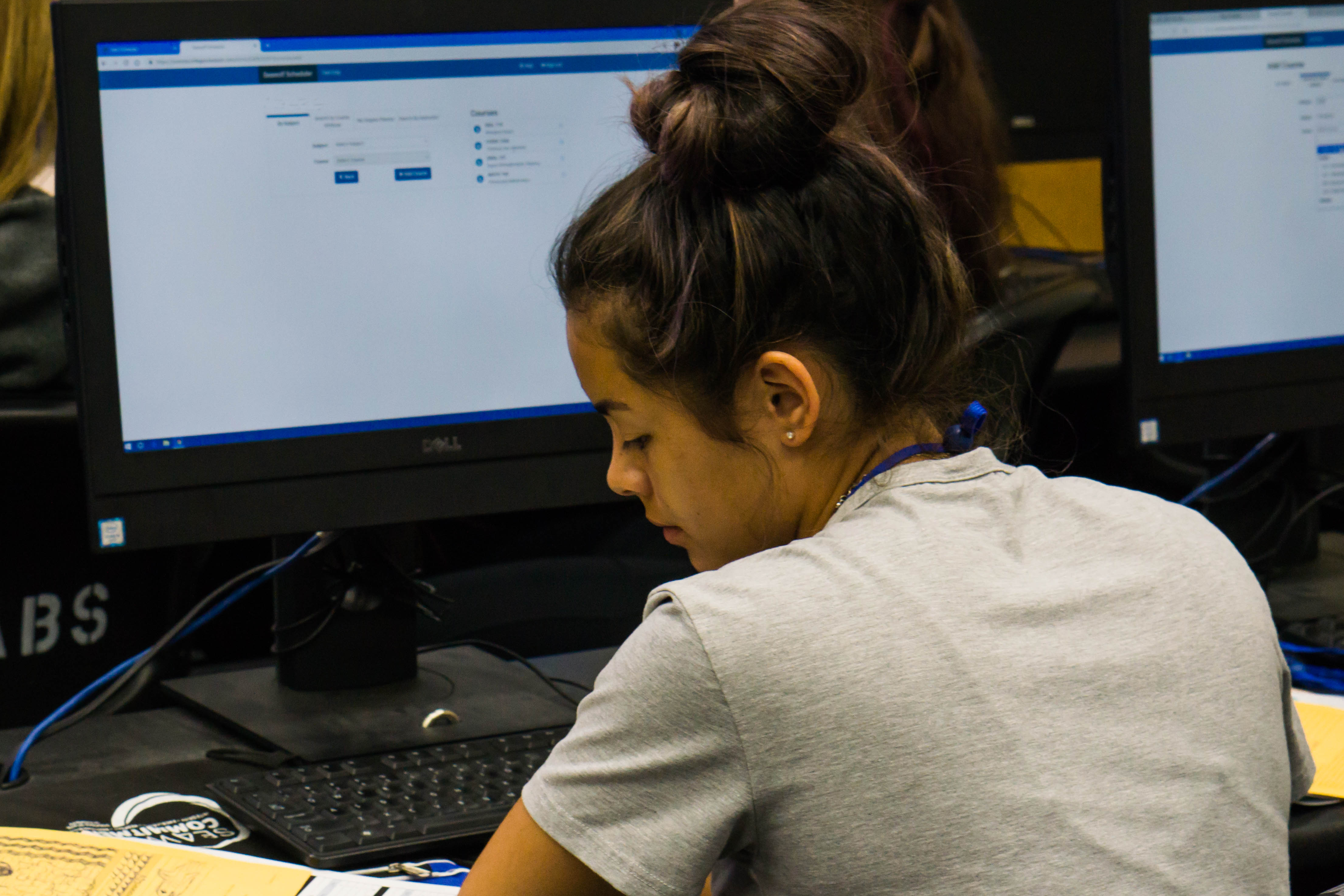 Student reads pages on to her left while sitting at computer