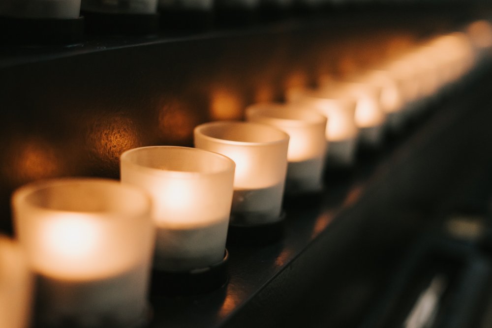 A row of lit votive candles glowing