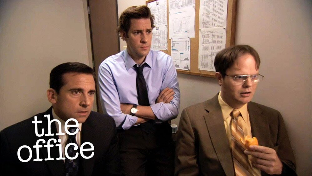 An image from the show 'The Office' of three men sitting in business attire 