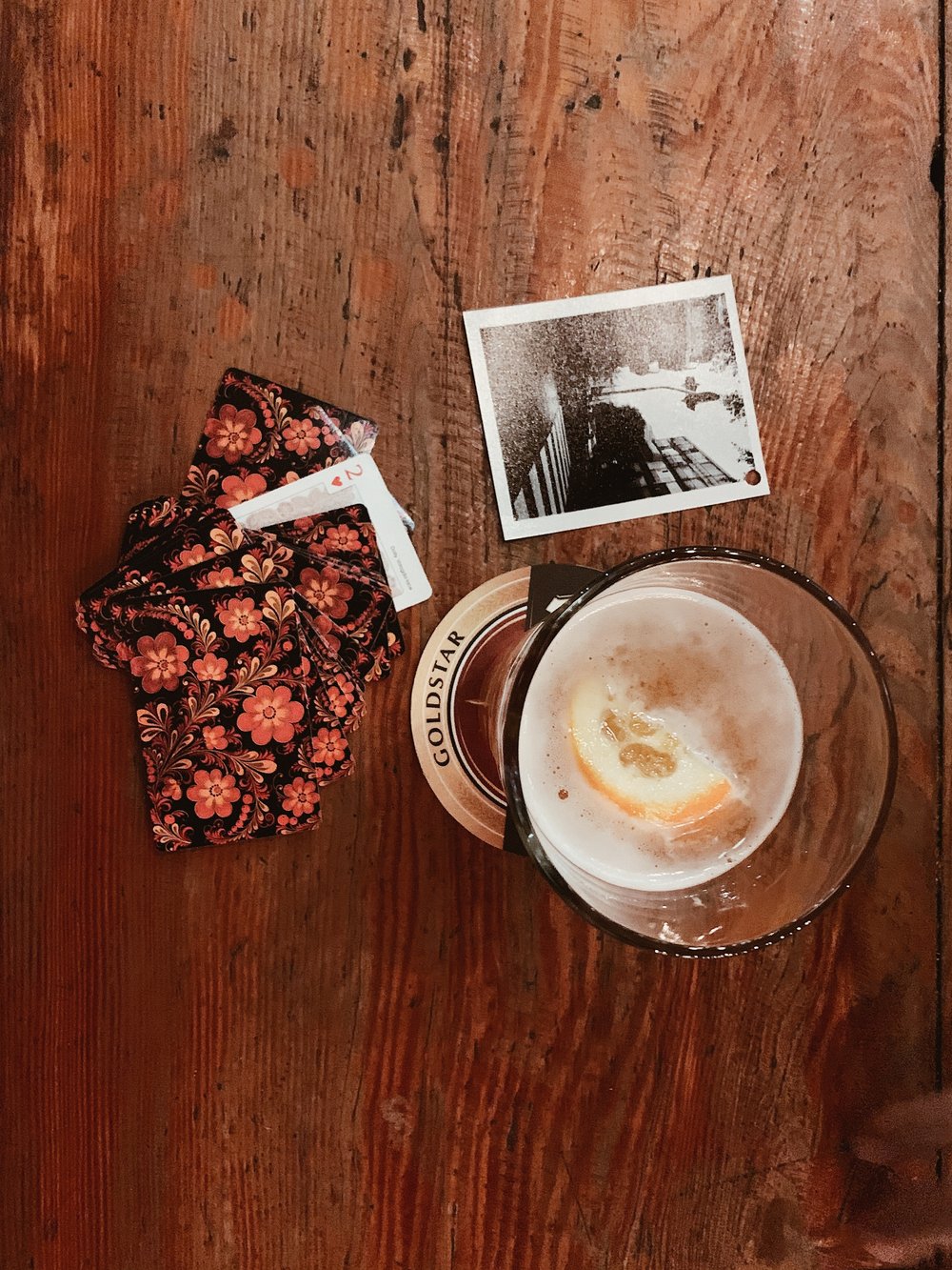 a drink next to a hand of playing cards and a photograph