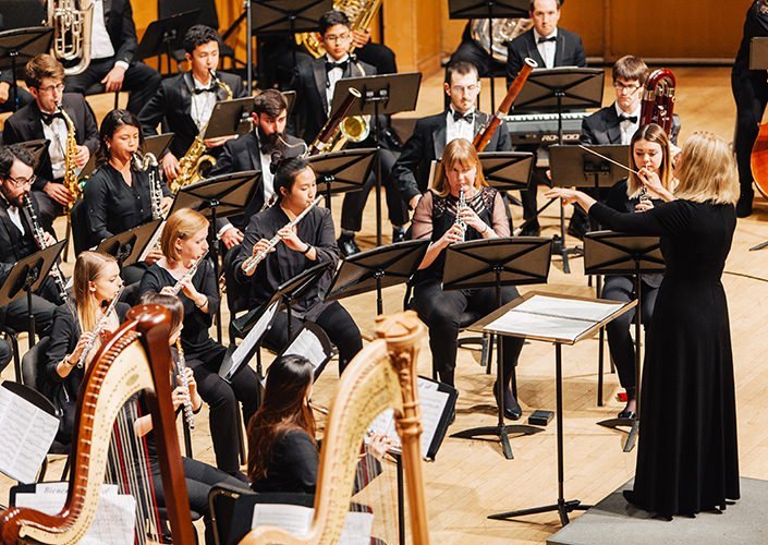 people playing various instruments and one person conducting them