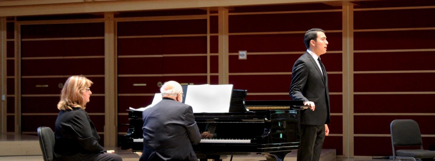 People dressed in black suits composing music on a stage inside the GMC