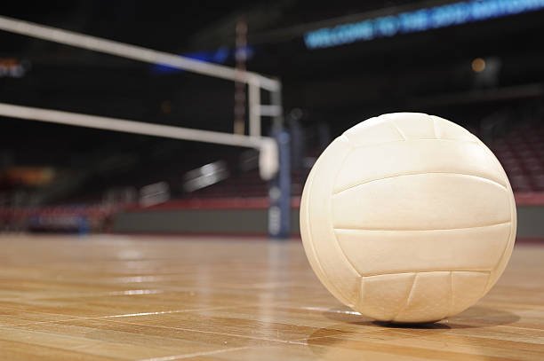 A volleyball sitting on the floor of an indoor volleyball court