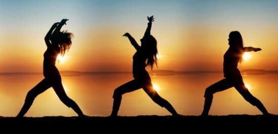 Three people doing three different yoga positions on the beach in front of the sunset