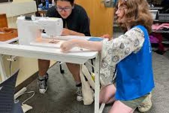 Someone helping someone else learn to sew