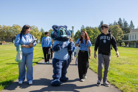 Students walking with Lobo (mascot)