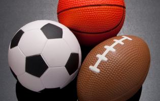 A soccer ball, a basketball, and a football