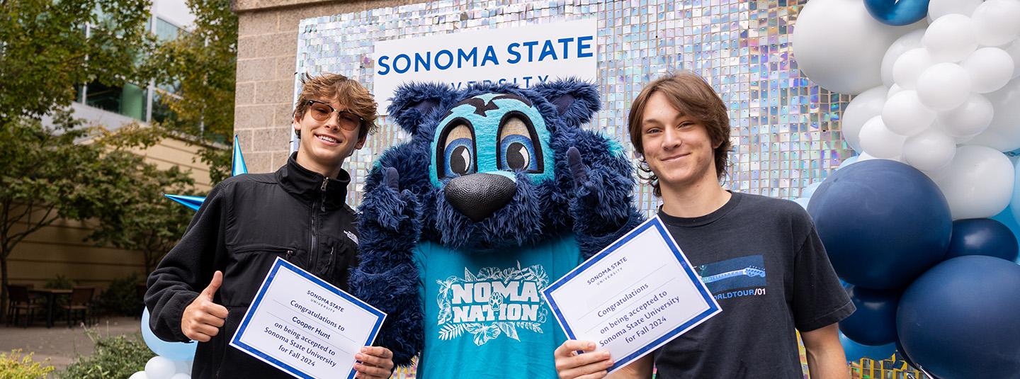 Two students hold certificates next to Lobo