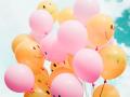 A bunch of pink and yellow balloons with smiley faces on them