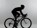 A black and white image of someone riding a bicycle indoors