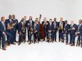 The members of the Lincoln Center Orchestra posing in formal attire with their instruments