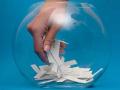 A hand reaching into a fishbowl to pick up a tab of paper 