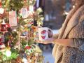a person holding a coffee mug next to a decorated Christmas tree