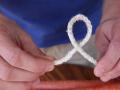 Two hands tying a white rope into a single loop