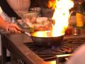 Someone cooking while a flame erupts from a pan on a stove