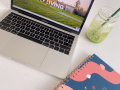 A colorful planner, a green iced drink in a glass jar with a green straw, and an open laptop with the words "Seawolf Living" on the screen