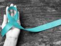 An image of a hand holding a turquoise ribbon