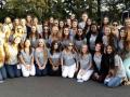 A large group of sorority members standing in rows and smiling while wearing sorority t-shirts